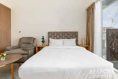 a bedroom with a large bed and a chair at Bespoke Holiday Homes - Cozy Modern Studio in Samia by Azizi in Dubai