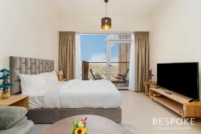 a bedroom with a bed and a large window and a television at Bespoke Holiday Homes - Cozy Modern Studio in Samia by Azizi in Dubai