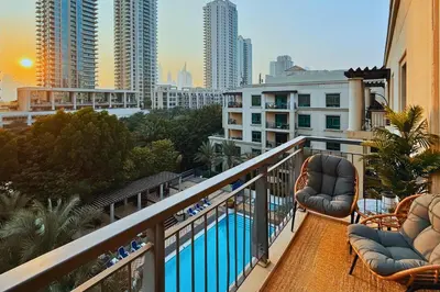 a balcony with chairs and a pool on a building at Luxe 1-BR with Pool Sunset Balcony View in The Greens in Dubai