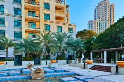 a courtyard with palm trees in front of a building at Luxe 1-BR with Pool Sunset Balcony View in The Greens in Dubai