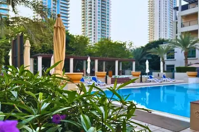 a swimming pool with chairs and an umbrella at Luxe 1-BR with Pool Sunset Balcony View in The Greens in Dubai