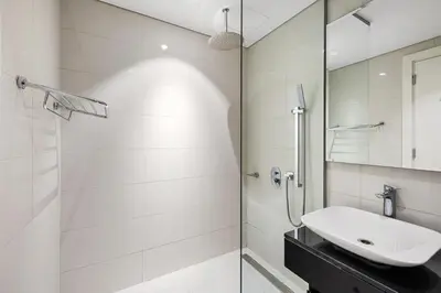 a white bathroom with a sink and a shower at Luxury Unit High Floor Damac Majestine in Dubai