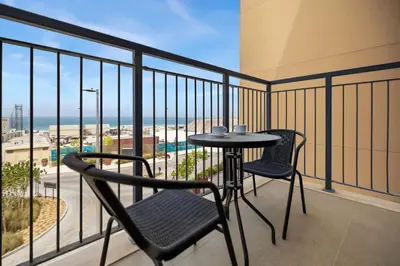a balcony with two chairs and a table at La Mer Le Pont 1 Bedroom Beachside Apartment in Dubai