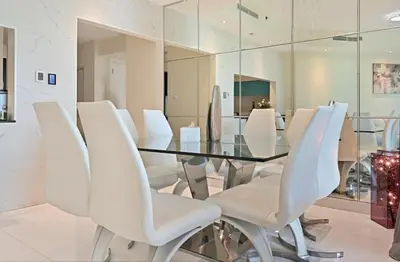 a dining room with a glass table and white chairs at Modern Luxury Upgraded 2BR Apartment The Greens in Dubai