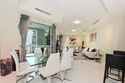 a living room with a glass table and white chairs at Modern Luxury Upgraded 2BR Apartment The Greens in Dubai