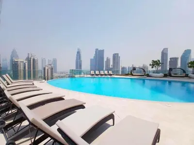 a swimming pool with lounge chairs and a city skyline at Walking Distance to Dubai Mall and Burj Khalifa, Easy Access to Dubai Marina, JBR Beach and Palm Jumeirah - Imperial Avenue, Downtown Dubai in Dubai