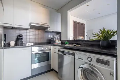 a kitchen with white cabinets and a washing machine at Frank Porter - Silverene Towers in Dubai