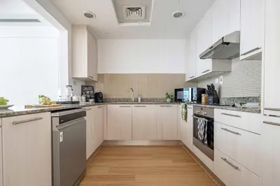 a kitchen with white cabinets and stainless steel appliances at Frank Porter - Bay Square in Dubai