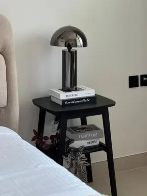 a table with a lamp and books on it next to a bed at Modern Studio at Binghatti Azure In Heart of JVC in Dubai