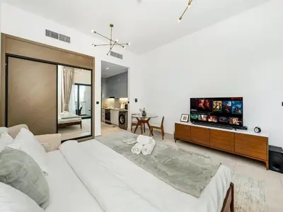 a bedroom with a large white bed and a flat screen tv at Luxe studio Downtown Burj Khalifa Skyline view in Dubai