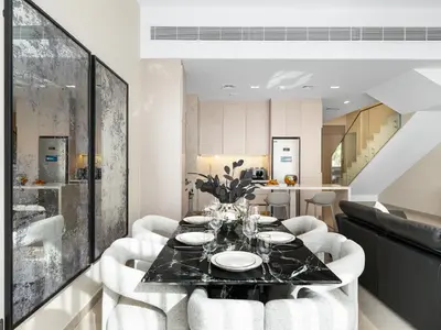 a dining room with a table and white chairs at LUX 4BD Villa, PS5, Minutes from Golf & Downtown in Dubai