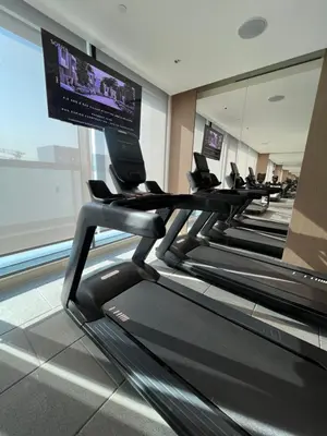 a row of treadmills in a gym with a flat screen tv at Deluxe 1BR with maid's room, 10 min to Downtown in Dubai