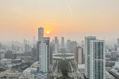 a city skyline with the sun setting in the sky at Private Pool - Amazing 1BR Apartment in JVC in Dubai