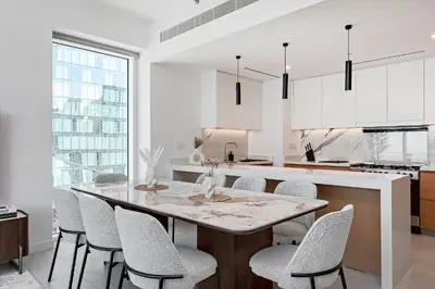 a white kitchen with a table and chairs at La Vie Apartments in Dubai