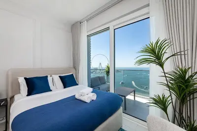 a bedroom with a bed and a large window at La Vie Apartments in Dubai