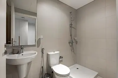 a white bathroom with a toilet and a sink at La Vie Apartments in Dubai