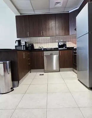 a kitchen with wooden cabinets and a stainless steel refrigerator at Elite Residence, Marina in Dubai