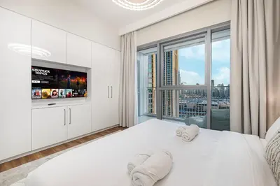 a bedroom with a white bed with a large window at Modern Downtown Apartment plus Pool plus Khalifa View in Dubai