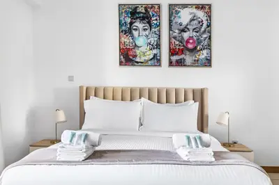 a bedroom with a bed with two pictures on the wall at Modern 1BR in Dubai Marina with Balcony Gym & Pool in Dubai