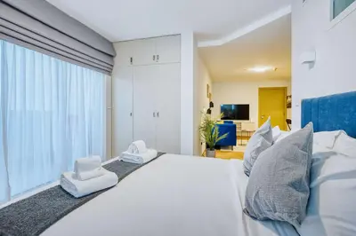 a bedroom with a large white bed with two white chairs at PVH - Dubai Gate 1 - Cozy Central Studio in JLT in Dubai