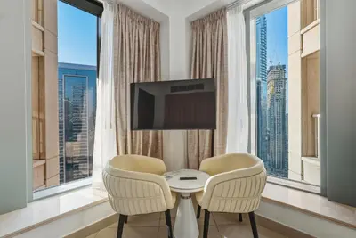 a living room with two chairs and a table and a tv at Downtown 1BR Full Burj Khalifa & Fountain Views in Dubai