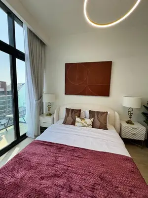 a bedroom with a large bed with a red blanket at Posh and Bright New Studio Apartment in Dubai