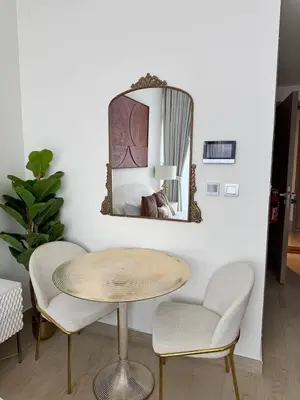 a room with a table and two chairs and a mirror at Posh and Bright New Studio Apartment in Dubai