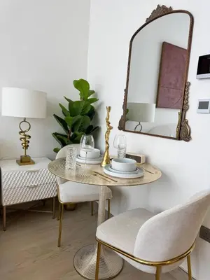a dining room with a table and chairs and a mirror at Posh and Bright New Studio Apartment in Dubai