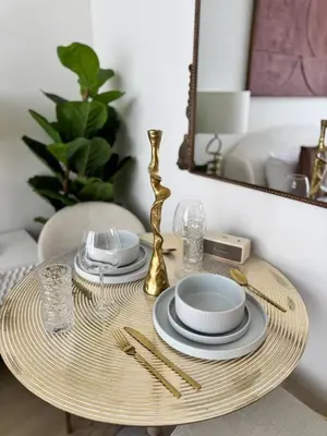 a rattan table with plates and glasses on it at Posh and Bright New Studio Apartment in Dubai
