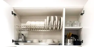 a kitchen cabinet filled with white dishes and utensils at 15 min from Dubai Marina & JBR beach Studio apartment AZURE BINGHATTI JVC in Dubai