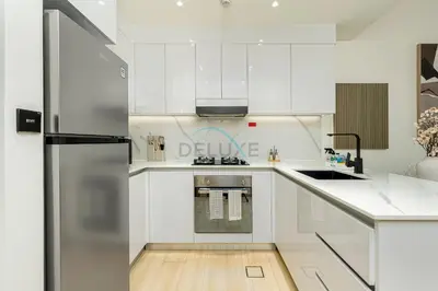 a kitchen with white cabinets and a stainless steel refrigerator at Located Near Community Parks, Convenient Stores, an RTA Bus Stop, And Just Minutes From The Mall - Binghatti Emerald, JVC by Deluxe Holiday Homes in Dubai