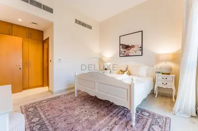a white bedroom with a bed and a table at 4BR plus Maids Room Villa Near Nad Al Sheba Mall, With Easy Access to Major Dubai Attractions - Nad Al Shiba Third, Nad Al Sheba by Deluxe Holiday Homes in Dubai