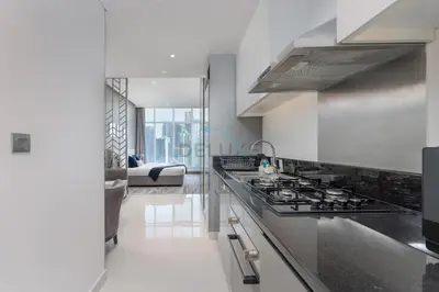 a kitchen with a stove top oven next to a living room at Dubai Water Canal View, Minutes away from Burj Khalifa and Dubai Mall, Near Metro Bus Station - Prive by Damac B, Business Bay by Deluxe Holiday Homes in Dubai