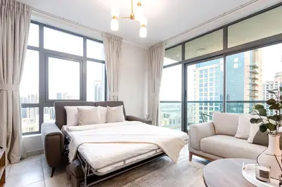 a bedroom with a bed and a couch and windows at Modern Retreat in The Views with Balcony & Pool in Dubai