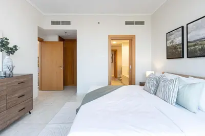 a bedroom with a white bed and a wooden dresser at Modern Retreat in The Views with Balcony & Pool in Dubai