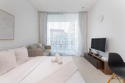 a white living room with a large window at High-Floor Studio Overlooking the Community, Just a Short Drive to Miracle Garden, Binghatti Azure, JVC by Deluxe Holiday Homes in Dubai
