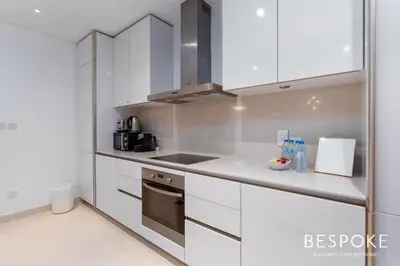 a kitchen with white cabinets and a stove top oven at Bespoke Holiday Homes - 2BR plus Kids room in City Walk with Direct Pool Access in Dubai