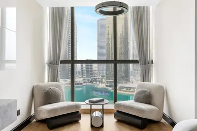 a living room with two chairs and a large window at Modern 1BR by the Lake Near DMCC Metro Station in Dubai