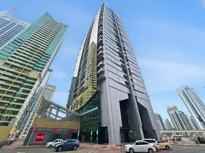 a tall building with cars parked in front of it at Modern 1BR by the Lake Near DMCC Metro Station in Dubai