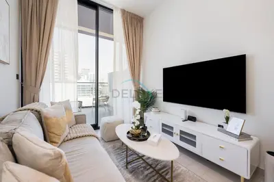 a white living room with a tv and a couch at Close to Community Park, Minutes Walk from Circle Mall, and Short Drive to Dubai Miracle Garden and Butterfly Garden - Binghatti Amber, JVC by Deluxe Holiday Homes in Dubai