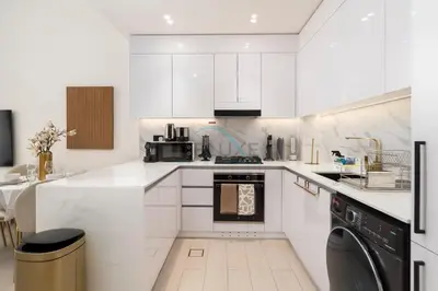 a white kitchen with a stove and a dishwasher at Close to Community Park, Minutes Walk from Circle Mall, and Short Drive to Dubai Miracle Garden and Butterfly Garden - Binghatti Amber, JVC by Deluxe Holiday Homes in Dubai