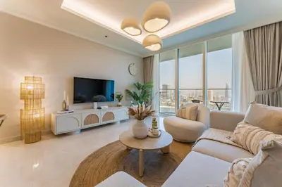 a living room with a couch and a tv at Prestigious Waterfront Community, Beachfront Living Near Dubai Marina and Top Dining Hotspots - Palace Beach Residence Tower 2, Emaar Beachfront by Deluxe Holiday Homes in Dubai