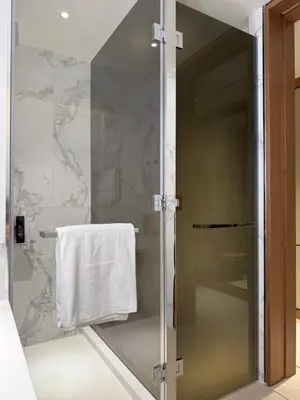 a bathroom with a glass shower with a white towel at Address Opera in Dubai