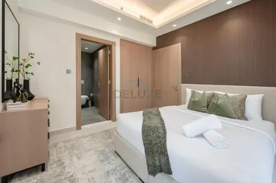 a bedroom with a large white bed and a bathroom at Modern 1BR Haven Near the Park, Offering Effortless Connectivity to Key Roads, Cloud A, Jumeirah Village Triangle by Deluxe Holiday Homes in Dubai