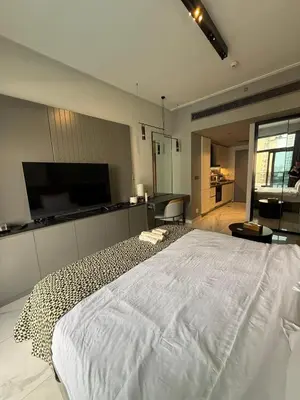 a bedroom with a white bed and a television at Furnished Studio 2 min Walk to Burji Khalifa in Dubai