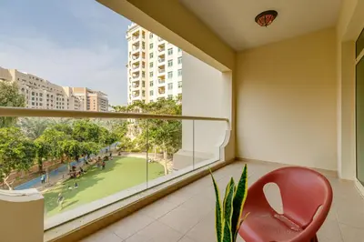 a red chair sitting on a balcony with a large window at Al Sarrood, Palm Jumeirah - 1 Bedroom Apartment - Allsopp & Allsopp in Dubai