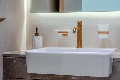 a white sink with a gold faucet in a bathroom at TRPS - Binghatti Royale, JVC - Private Pool, Luxury Furnished, Brand New in Dubai