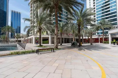 a park with palm trees and benches and buildings at GuestReady - 1BR | Elegant Duplex | JLT in Dubai