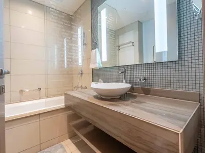 a bathroom with a sink and a mirror and a tub at Paramount Tower - Stylish 2BR Apartment with Balcony & Pool - Near Dubai Mall in Dubai