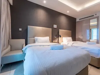 a hotel room with two beds and a chair at Paramount Tower - Stylish 2BR Apartment with Balcony & Pool - Near Dubai Mall in Dubai